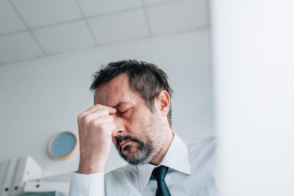 Business owner headache concept, businessman with painful migraine in office